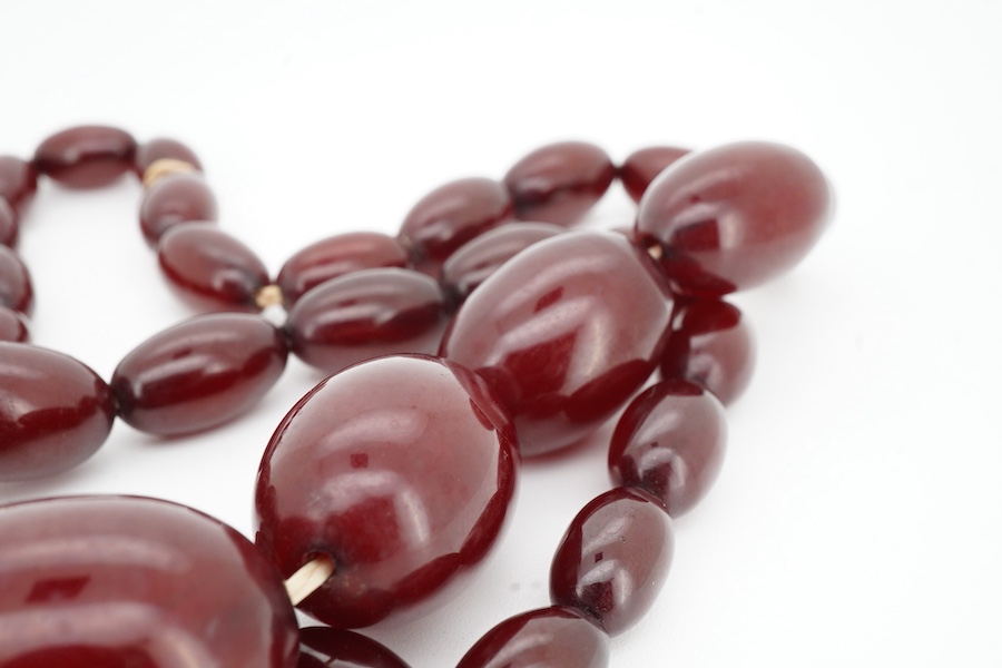 A cherry-coloured bakelite imitation amber necklace, composed of graduated oval beads measuring approximately 1.2-3cm, length 56cm, gross weight approximately 54 grams
